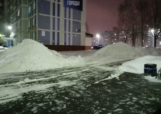 Коммунальщики складируют убранный во дворе снег около подъезда