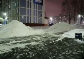 Коммунальщики складируют убранный во дворе снег около подъезда